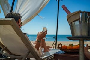 a woman sitting in a chair on the beach holding a glass at HVD Nympha Hotel - Adults Only - Private Beach & Free Parking in Golden Sands