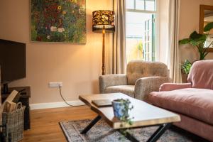 a living room with a couch and two chairs and a tv at The Dovecot in Salisbury