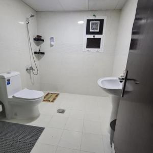 een witte badkamer met een toilet en een wastafel bij Ghurfati in Abu Dhabi