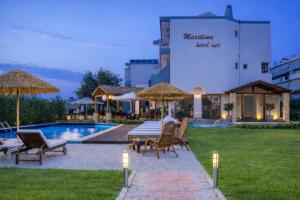 ein Hotel mit einem Tisch und Stühlen neben einem Pool in der Unterkunft Maritina Apartments in Ixia