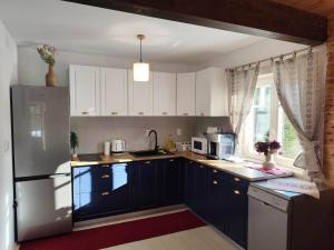 a kitchen with white cabinets and a refrigerator at Cabana Katica 3 Vendégház in Joseni