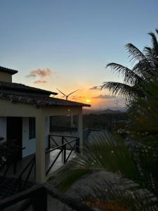 a sunset over a house with a windmill in the background at Pousada por do sol in Monte das Gameleiras
