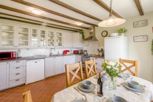 eine Küche mit weißen Schränken und einem Tisch mit Stühlen in der Unterkunft 3 Bed in Low Row oc-h34097 in Gunnerside