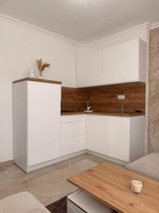 a kitchen with white cabinets and a wooden table at Apartman Andrea in Brčko