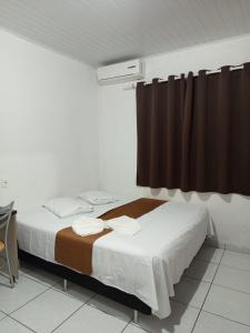 a bedroom with a large bed with brown curtains at Hotel BLESS in Cascavel