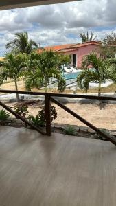 a balcony with a view of a house with palm trees at Pousada por do sol in Monte das Gameleiras