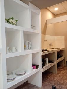 una cucina con ripiani bianchi con piatti e un lavandino di Alojamiento Gral Alvear a General Alvear