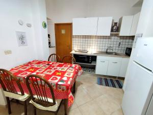 een keuken met een tafel en stoelen met een rode tafelkleed bij La Casa Di Via Marzulli in Acireale