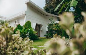 een wit huis met planten op de voorgrond bij Nong Lam Ecolodge in Linh Xuân Thôn