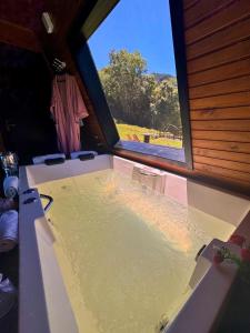 een bad in een kamer met een groot raam bij Chalé Aconchego Alfredo Wagner in Alfredo Wagner