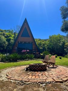 een vuurplaats en twee banken voor een gebouw bij Chalé Aconchego Alfredo Wagner in Alfredo Wagner