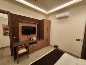 a living room with a tv and a couch in a room at Den Inn in Hisār