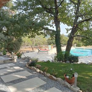 einen Hinterhof mit einem Pool und einem Picknicktisch in der Unterkunft Sous les chênes in Lussan