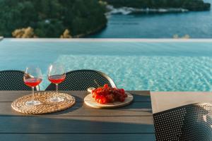 two glasses of wine and a plate of fruit on a table by a pool at Kohyli Villas in Meganisi +76 photos