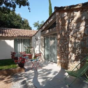 eine Terrasse mit Stühlen und einem Tisch vor einem Steingebäude in der Unterkunft Sous les chênes in Lussan