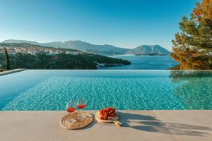 a table with two glasses and a bowl of fruit next to a pool at Kohyli Villas in Meganisi