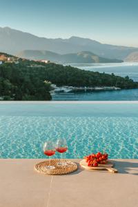 two glasses of wine sitting on a table next to a pool at Kohyli Villas in Meganisi