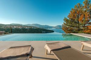 a swimming pool with two chairs and a view of a lake at Kohyli Villas in Meganisi