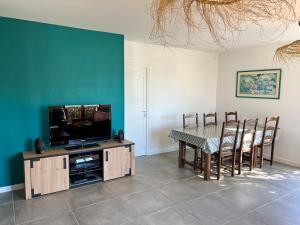 ein Esszimmer mit Tisch und Fernseher in der Unterkunft Résidence du Moulin Girard in Jard-sur-Mer