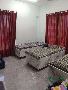 three beds in a room with red curtains at Riyas stay in Mumbai