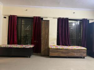two beds in a room with red curtains at Riyas stay in Mumbai