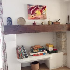 ein Regal an einer Wand mit Büchern darauf in der Unterkunft Sous les chênes in Lussan