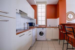 une cuisine aux murs orange et un lave-linge/sèche-linge. dans l'établissement L' Harmonie, à Périgueux
