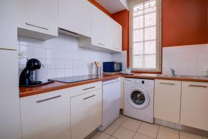 une cuisine avec des armoires blanches et une machine à laver dans l'établissement L' Harmonie, à Périgueux 13 autres photos