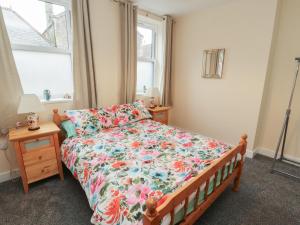 a bedroom with a bed with a floral comforter and two windows at 20 Lorton Street in Cockermouth