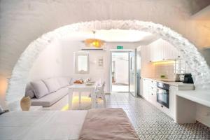 a white room with a bed and a kitchen at Suite Amalaya Κατώι in Kithnos