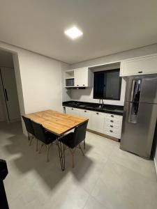 a kitchen with a wooden table and a refrigerator at Flat Bugayalê Lounge in Garanhuns