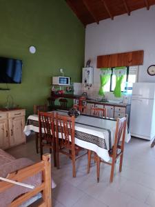 een keuken met groene muren en een tafel en stoelen bij Arevalo Mar de Ajo in Mar de Ajó