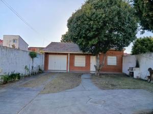 een rood bakstenen huis met een boom op de oprit bij Arevalo Mar de Ajo in Mar de Ajó