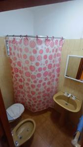 a bathroom with a pink shower curtain and a toilet and sink at Arevalo Mar de Ajo in Mar de Ajó +70 photos