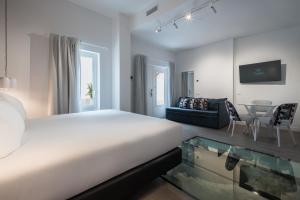 a white bedroom with a bed and a table at Tandem Mezquita in Córdoba