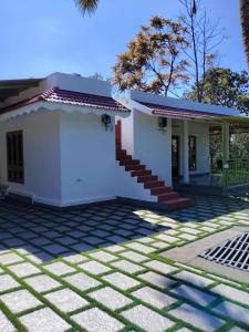 a small white house with a staircase in a yard at VLand homestay in Vagamon