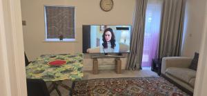 een woonkamer met een televisie met een vrouw erop bij SNS dreams property in Dunstable