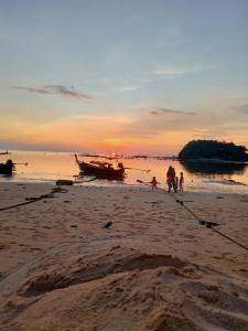 een groep mensen die op een strand lopen met een boot bij Langkao Homestay Kohlibong หลังเขาโฮมสเตย์ เกาะลิบง in Ko Kwang
