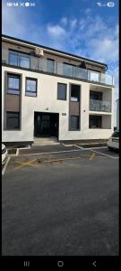 een groot wit gebouw met een parkeerplaats bij Aerodrom apartman in Ledine