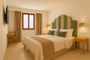 een slaapkamer met een groot bed en een televisie bij Hotel Boutique Petit París in Port de Pollença