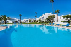 a large swimming pool with blue chairs and buildings at WindMill Rooftop Panoramic OceanView Condo By BeCherish in Albufeira