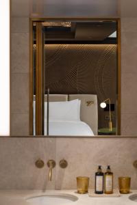a bathroom mirror with a sink and a bed at Almanac Palais Vienna in Vienna