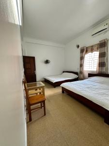 a bedroom with two beds and a chair and a table at Tay Bac Hotel in Mộc Châu