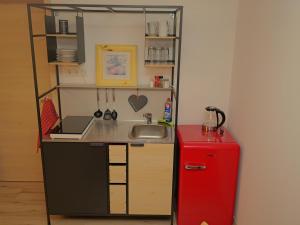 a small kitchen with a sink and a red refrigerator at elfA-partment in Schwanstetten