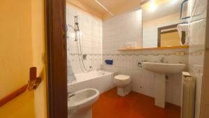 een badkamer met een wastafel, een toilet en een ligbad bij Hostdomus - Betulle Apartments in Sestriere