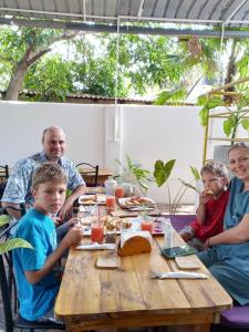 a family sitting around a wooden table eating food at La PRINCE Hostel and hotel in Trincomalee