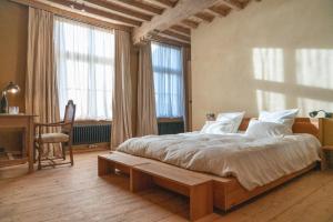 a bedroom with a bed and a desk and windows at Eikenbrand in Veurne