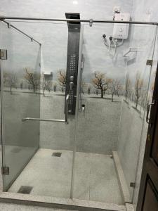 a shower with a glass door with a picture of a field at Kaarasaaram inn in Avarankal