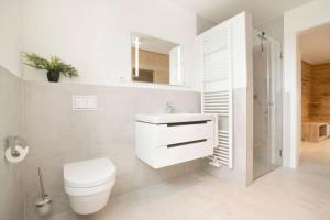 a white bathroom with a toilet and a sink at Dahmer Strand 5 in Dahme +26 photos