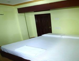 a bedroom with a bed with white sheets and a door at Spot On V GUST IN in Tenāli